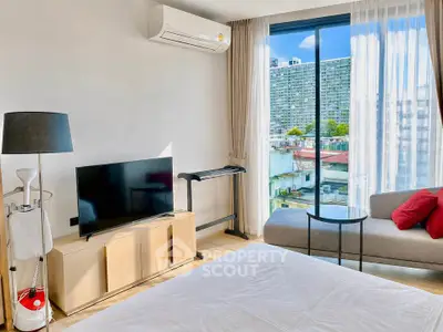Modern bedroom with city view, featuring sleek furniture and large window for natural light.