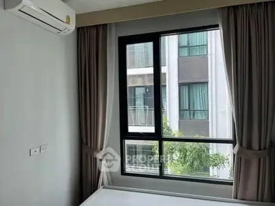 Modern bedroom with large window and air conditioning, offering a view of neighboring building.