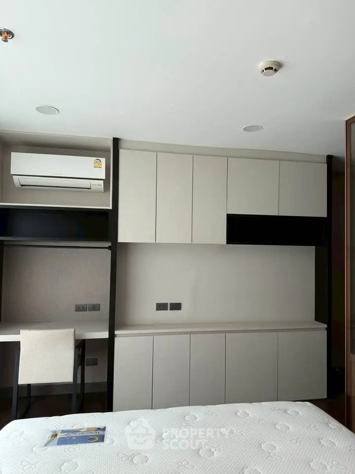 Modern bedroom with built-in storage and workspace, featuring sleek design and air conditioning.