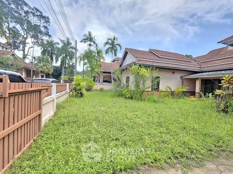 Charming suburban house with lush green lawn and tropical trees, perfect for family living.