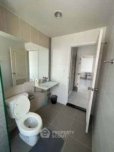 Modern bathroom with sleek design and neutral tones, featuring a large mirror and contemporary fixtures.