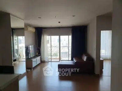 Spacious living room with balcony and city view, featuring modern furniture and ample natural light.