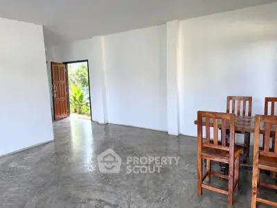 Spacious open-plan living area with polished concrete floors and wooden dining set.