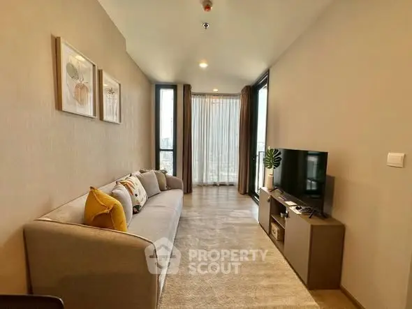 Modern living room with cozy sofa and TV, featuring large windows and stylish decor.