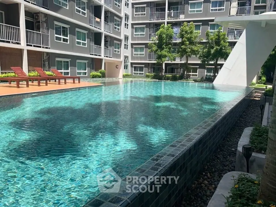 Luxurious apartment complex with stunning outdoor pool and sun loungers, perfect for relaxation.