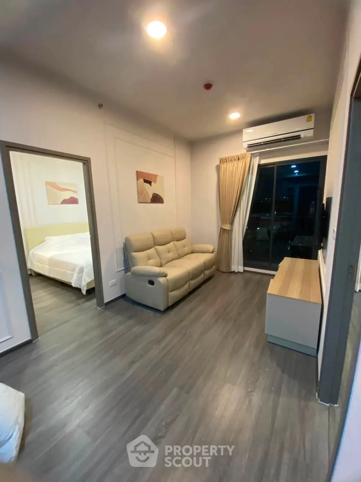 Modern living room with cozy sofa, stylish decor, and large window offering natural light.