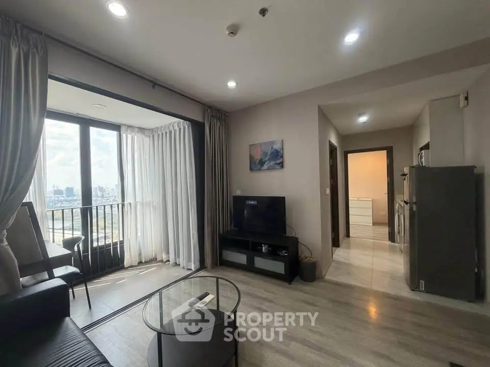 Modern living room with city view, sleek furniture, and natural light in a high-rise apartment.