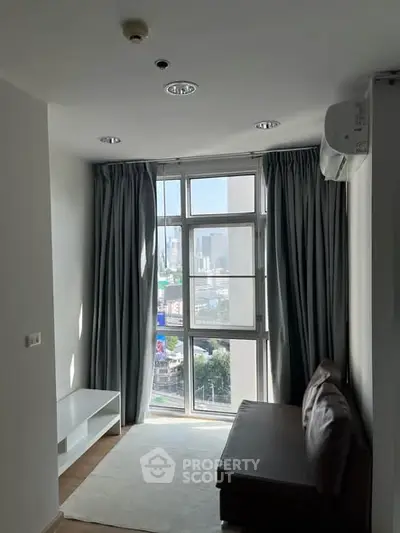 Cozy living room with large window offering city view, modern furniture, and natural light.