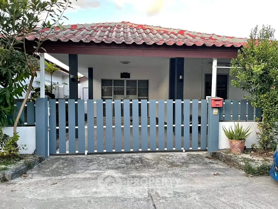 Charming single-story home with tiled roof and gated front yard, perfect for family living.