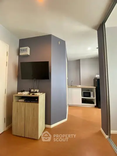 Modern apartment interior with TV and kitchenette, featuring sleek design and efficient use of space.