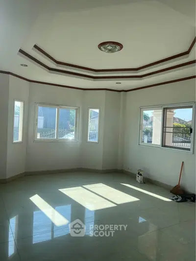 Spacious sunlit room with large windows and elegant ceiling design