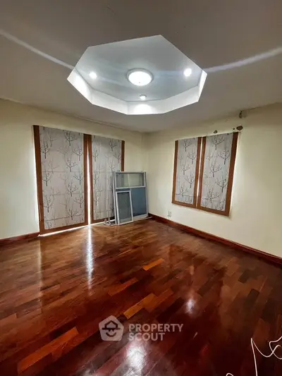 Spacious room with wooden flooring and elegant ceiling lights, perfect for a cozy living space.