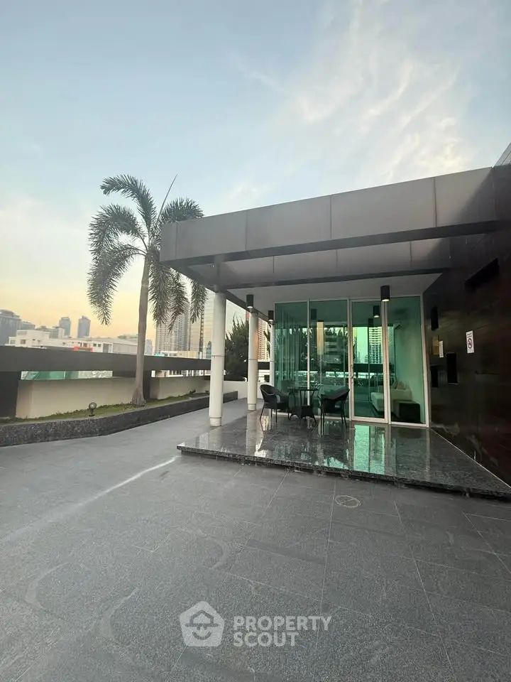 Modern building entrance with sleek design and palm tree, showcasing urban elegance and luxury.