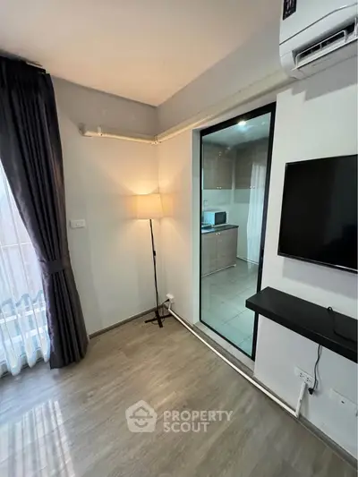 Modern living room with sleek flooring and glass door to kitchen