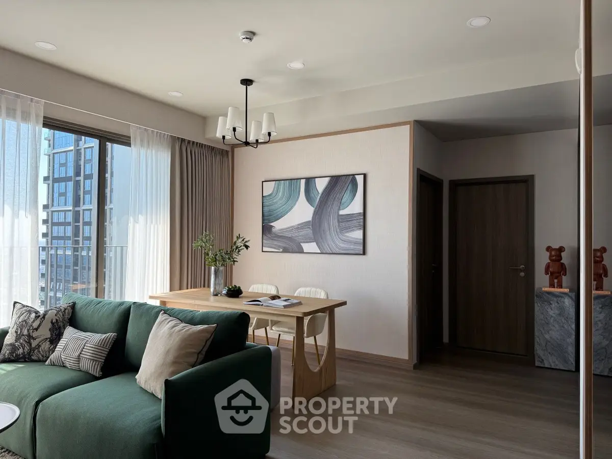 Modern living room with green sofa, dining table, and large window with city view.