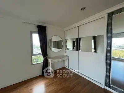Spacious bedroom with elegant wooden flooring and large mirrored wardrobe