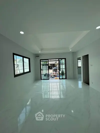 Spacious modern living room with large windows and marble flooring, offering abundant natural light.