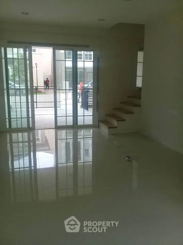 Spacious living room with large glass doors and staircase