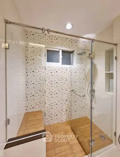 Modern bathroom with glass shower enclosure and terrazzo wall tiles
