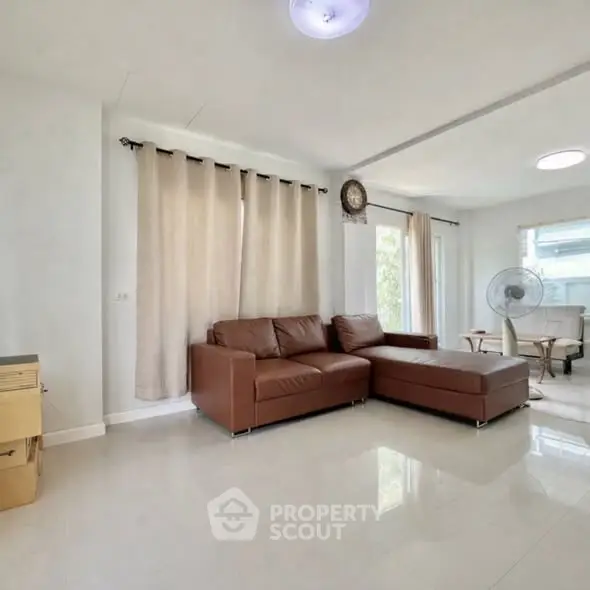 Spacious living room with modern brown leather sofa and natural light