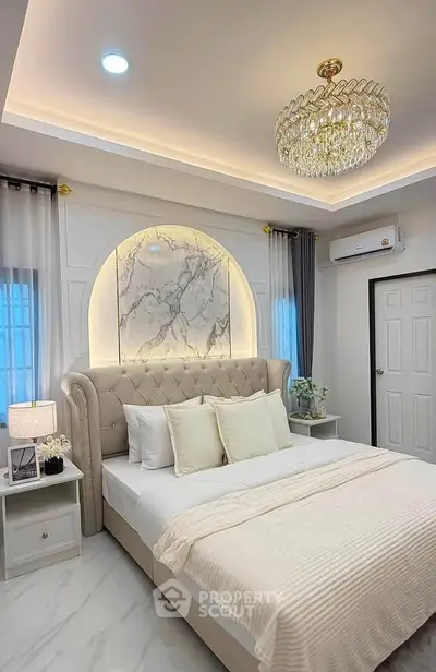 Luxurious bedroom with elegant chandelier and plush bed in modern apartment.