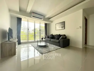 Spacious modern living room with large windows and stylish decor in a bright apartment.