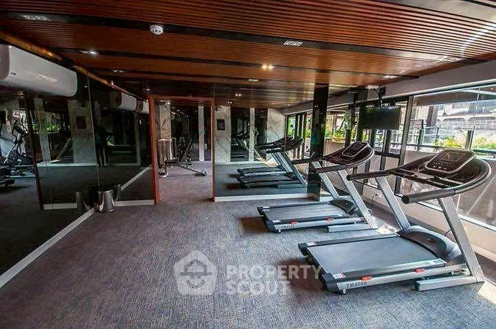 Modern gym with treadmills and mirrored walls in luxury apartment complex.