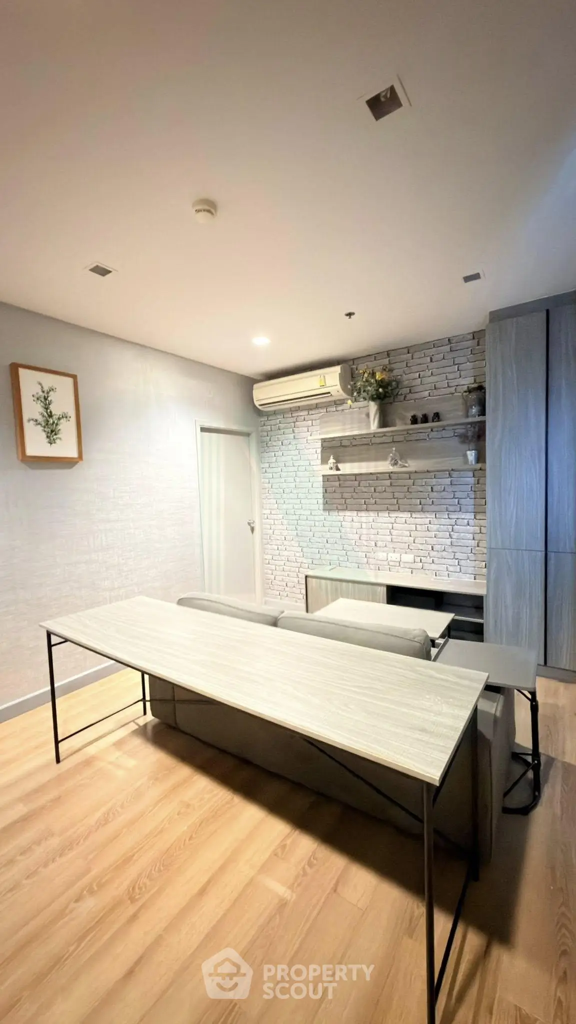 Modern living room with stylish decor and wooden flooring, featuring a sleek table and wall-mounted shelves.