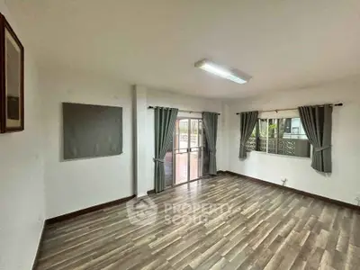 Spacious living room with wooden flooring and large windows for natural light.