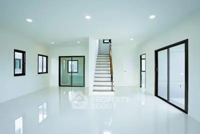 Spacious modern living room with sleek staircase and large windows