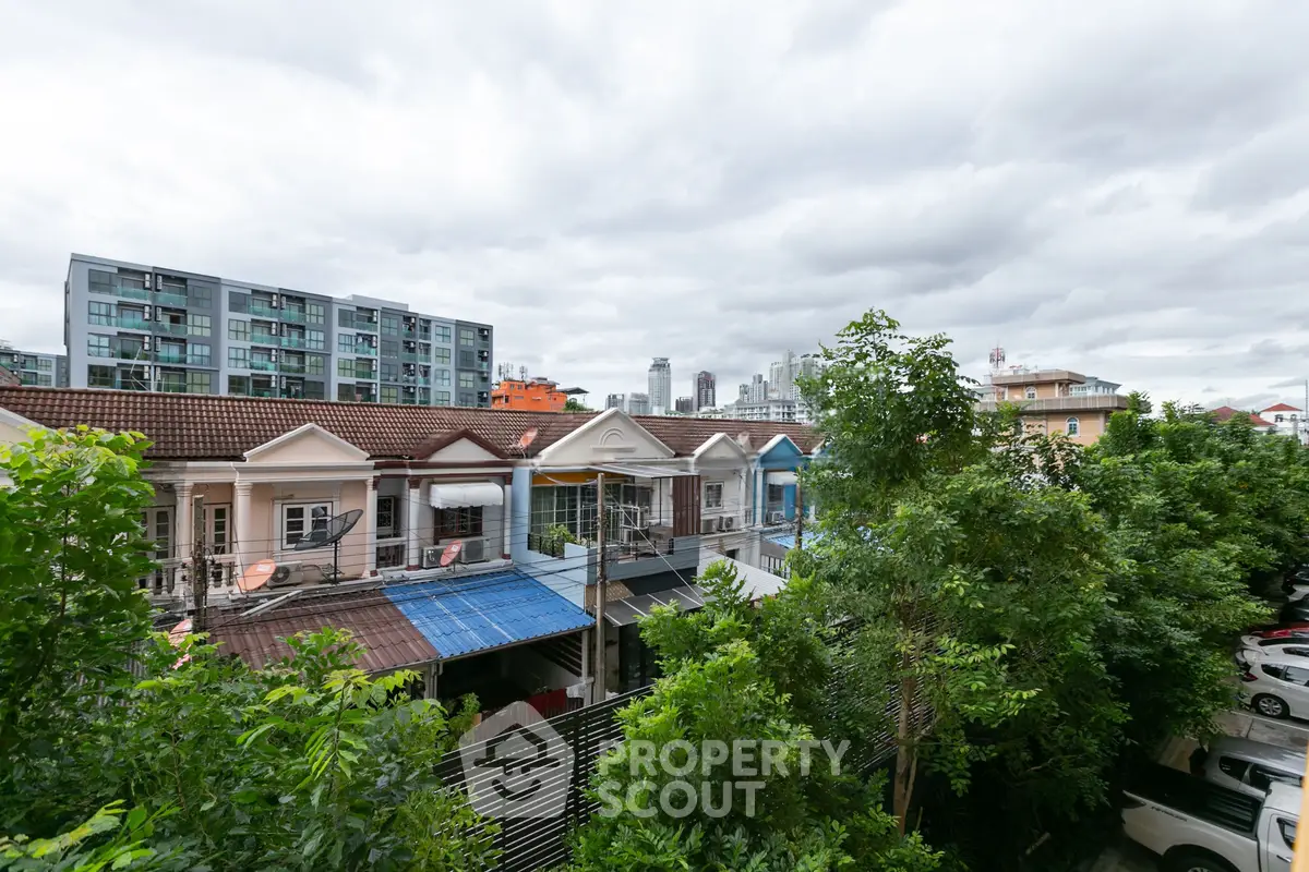 Charming urban view with residential houses and modern buildings under a cloudy sky.