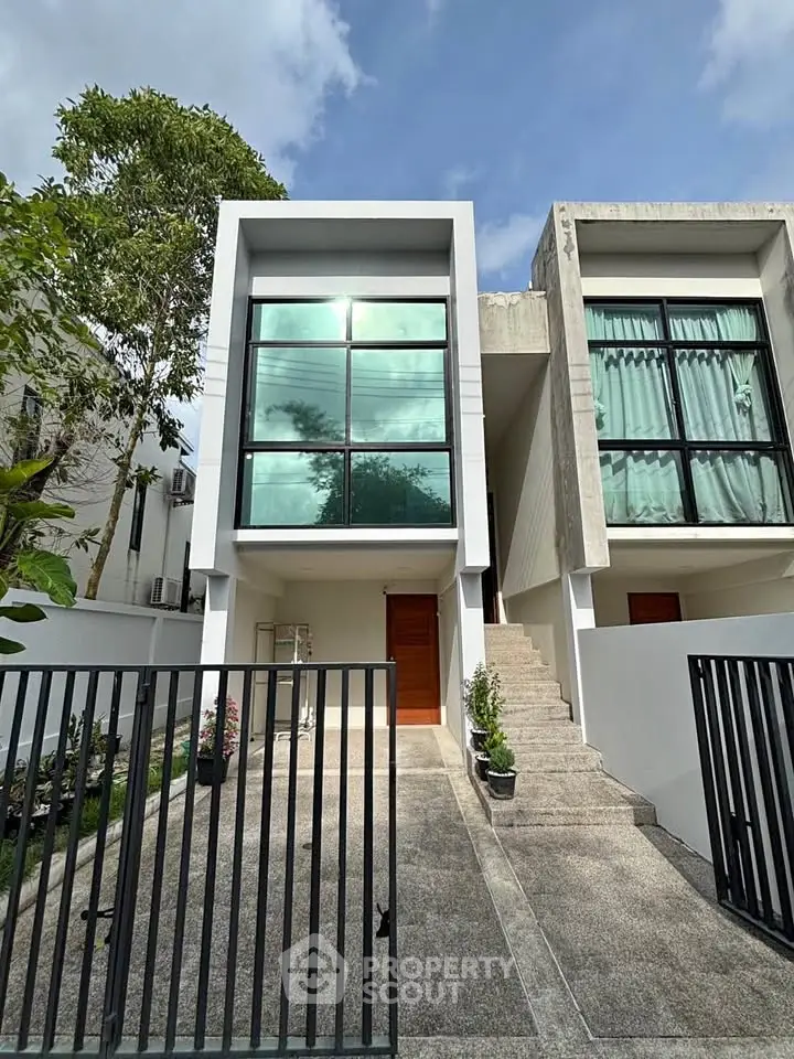 Modern townhouse exterior with large windows and gated entrance, showcasing contemporary architectural design.