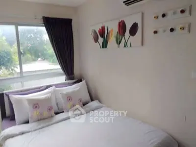 Cozy bedroom with floral decor and large window offering natural light.