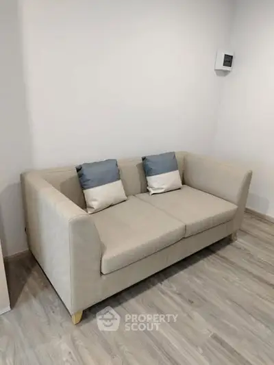 Modern beige sofa with cushions in a minimalist living room setting.