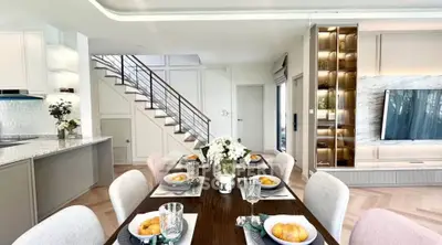 Elegant open-plan living and dining area with modern decor and stylish staircase