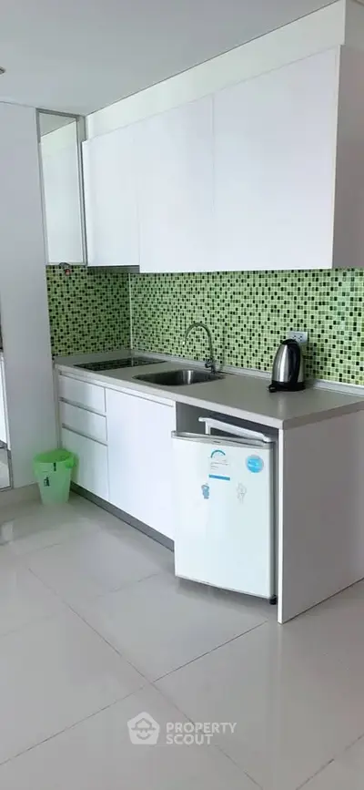 Modern kitchen with sleek white cabinets and green mosaic backsplash