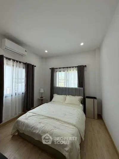 Cozy bedroom with natural light and modern decor, featuring a comfortable bed and air conditioning.