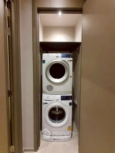 Compact laundry area with stacked washer and dryer in modern apartment.