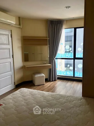 Cozy bedroom with large window and stylish decor in modern apartment.
