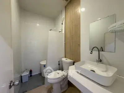 Modern bathroom with sleek fixtures and minimalist design, featuring a spacious sink and contemporary toilet.