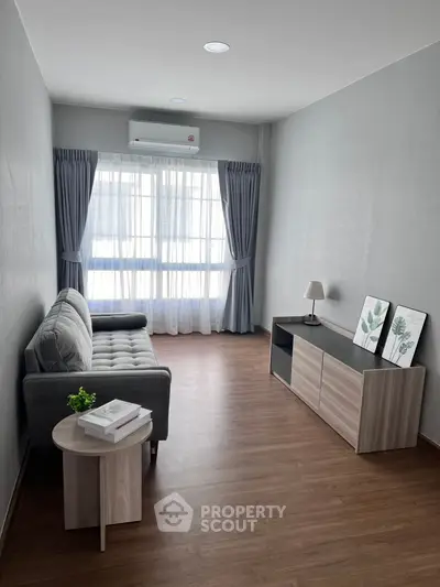 Modern living room with sleek furniture and large window, perfect for cozy relaxation.