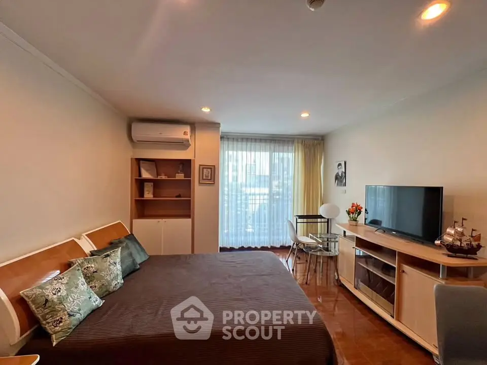 Cozy bedroom with modern decor, featuring a large bed, TV, and natural light from a window.