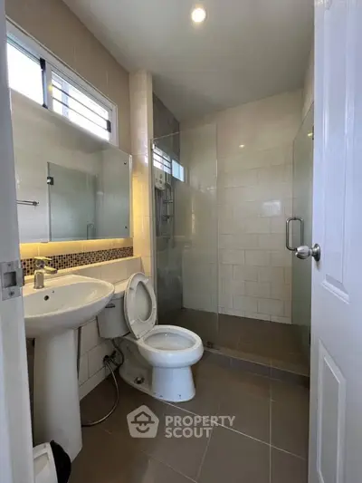 Modern bathroom with glass shower, white fixtures, and tiled walls in a contemporary home.