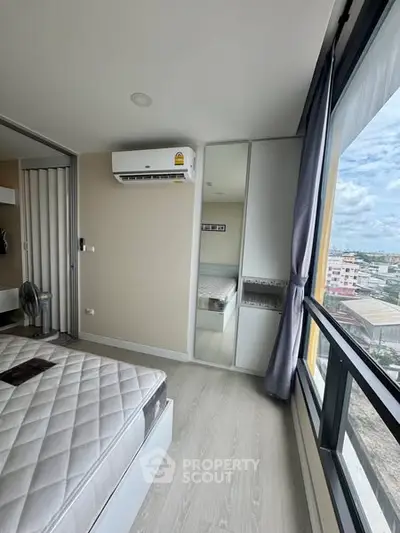 Modern bedroom with large windows and city view, featuring air conditioning and sleek design.