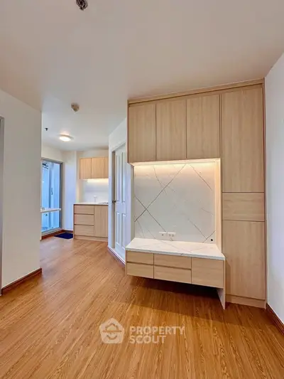 Spacious modern living area with wooden flooring and built-in storage cabinets.