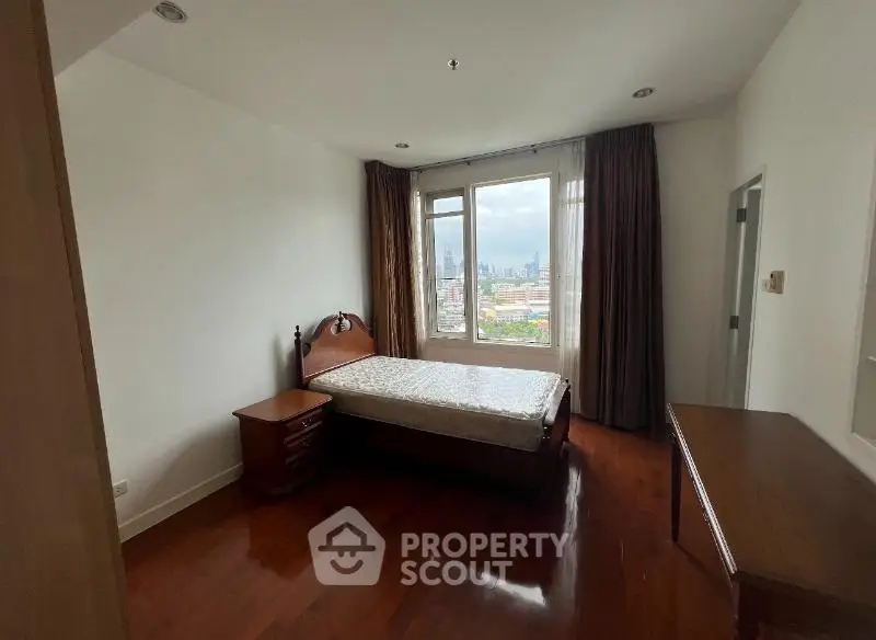 Spacious bedroom with city view and elegant wooden furniture