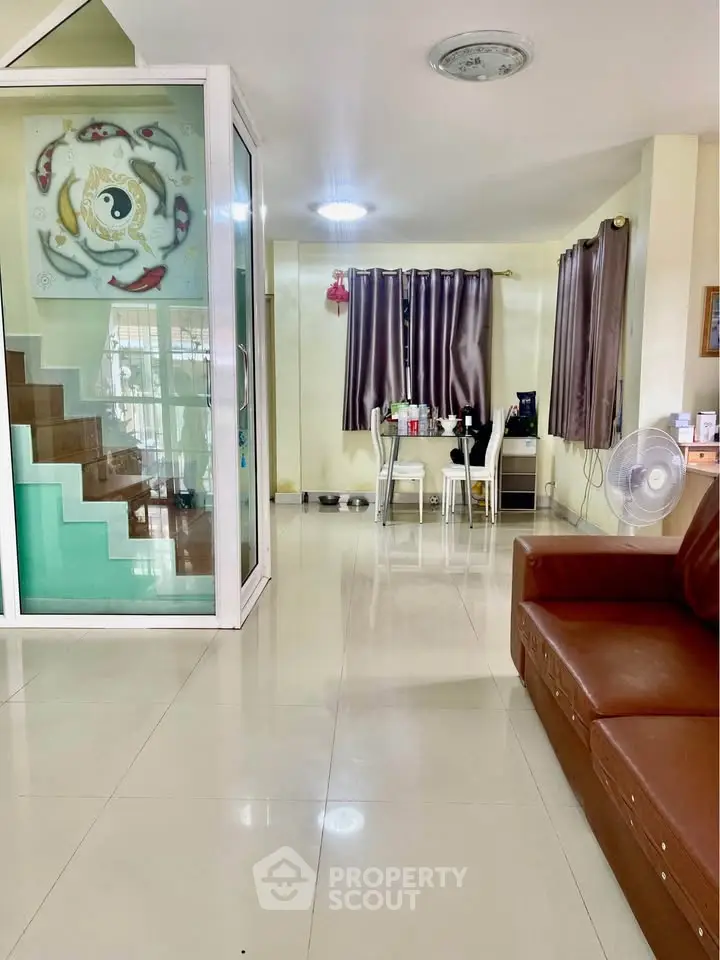 Spacious living room with modern decor and dining area, featuring a unique staircase design.