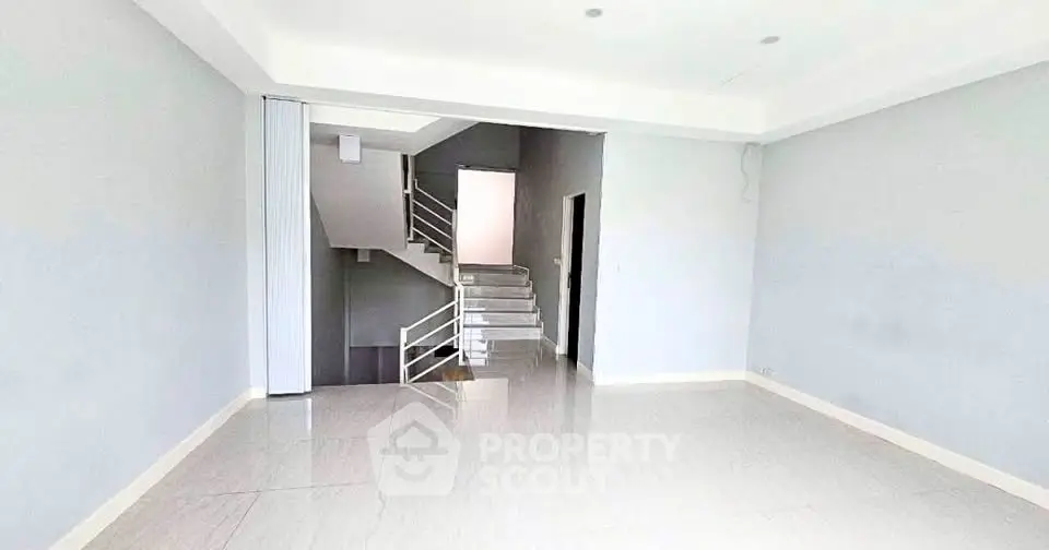 Spacious modern living room with sleek staircase and minimalist design.