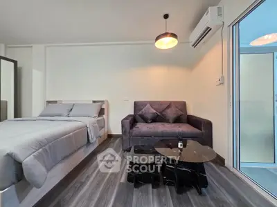 Modern studio apartment with cozy bed and stylish sofa in open layout.