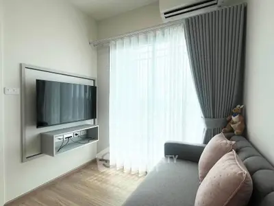 Modern living room with sleek TV setup and cozy sofa, featuring elegant curtains and natural light.